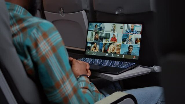 African american passenger talking to business people on videocall teleconference, meeting with colleagues on remote videoconference. Flying with airplane and chatting online. Close up.