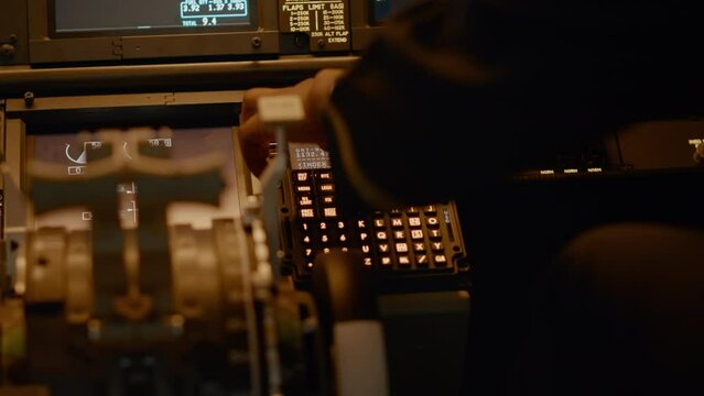 Male copilot inserting flight coordinates to arrive at destination, using dashboard command for navigation. Control panel power buttons and aviation compass, flying aircraft. Close up.