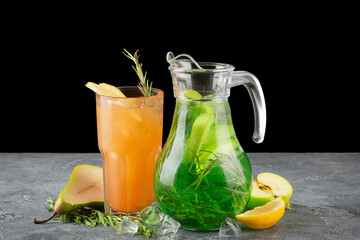 Cold refreshing lemonades with pear apple lemon and rosemary on dark background on gray table