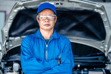 Auto mature mechanic repairman in uniform standing cross arms looking confident in the garage, positive thinking, repair and maintenance service concept.