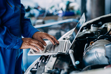 Automotive mechanic repairman using laptop computer and checking engine in the engine room, check...