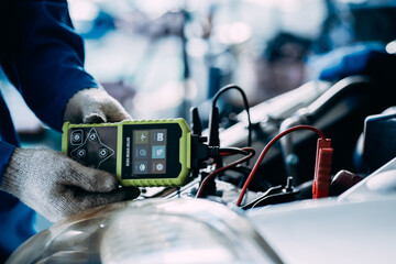 close up view of automotive mechanics repairman using a digital battery tester to check and analyze...