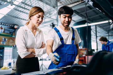 Automotive mechanic repairman talking to a female customer at the garage, check the mileage of the car, oil change, auto repair service concept.