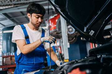 Fototapeta na wymiar Automotive mechanic repairman checking engine oil level engine in the engine room, check the mileage of the car, oil change, auto maintenance service concept.