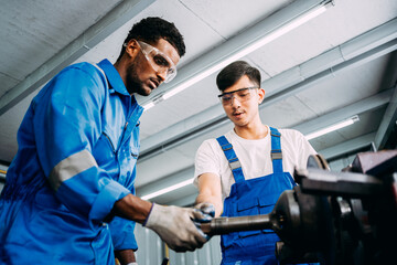 Auto mechanic repairman in uniform working with a grinding machine to surfaces polishing disc brake drum in the garage, Repair car brake system service center.