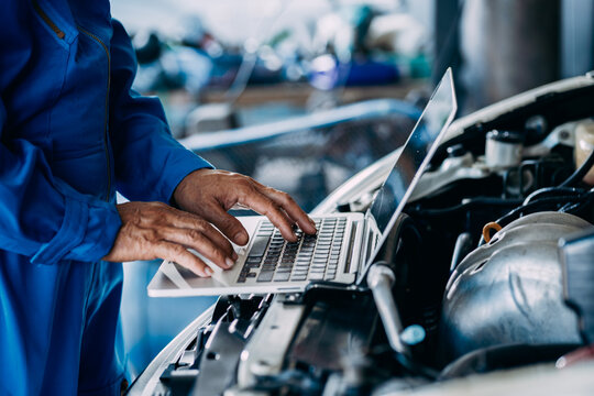 Automotive mechanic repairman using laptop computer and checking engine in the engine room, check the mileage of the car, oil change, auto maintenance service concept