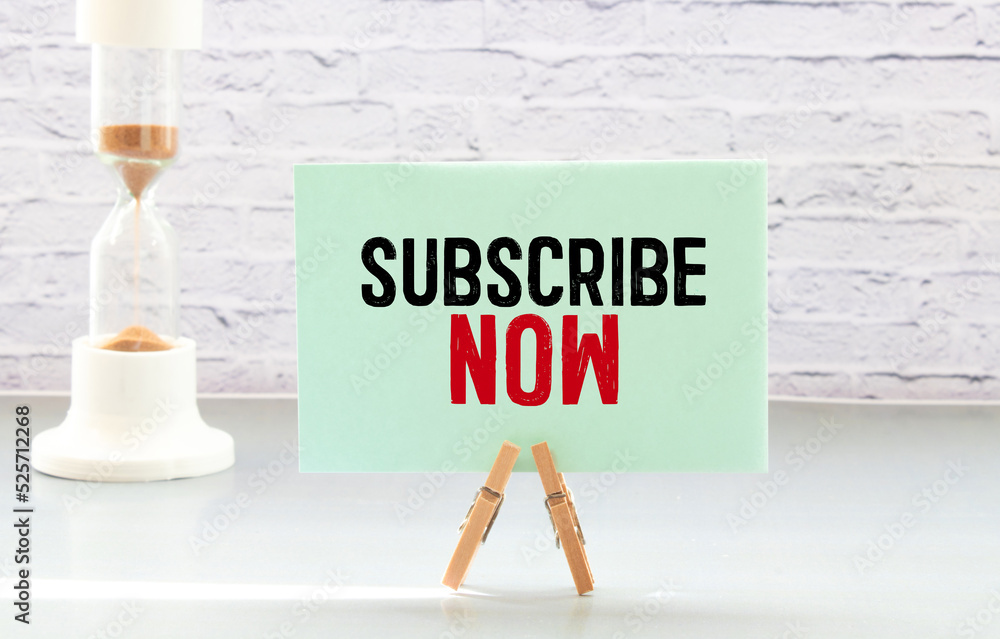 Poster on a white notepad, a red pen, a red notepad and a white sheet of paper with the text subscribe now.