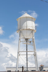 White Water Tower on Top of a Building Against a Cloudy Sky