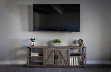 Large Flatscreen Television With a TV Stand With Decorations and Gray Wall and Dark Grey Carpet