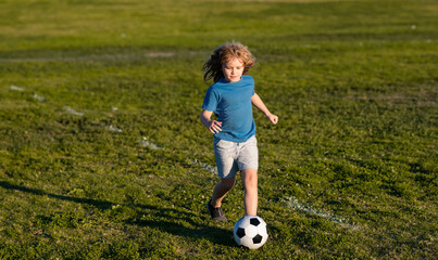 Soccer kid boy playing football. Child boy play football on outdoor field. Children score goal at...