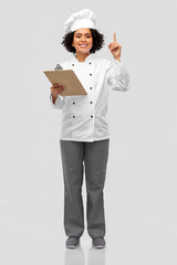 cooking, culinary and people concept - happy smiling female chef in toque and jacket with clipboard showing thumbs up over grey background