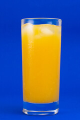 Single glass of orange juice isolated on blue background, vertical