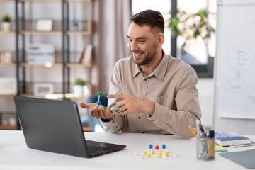 distance education, school and remote job concept - happy smiling male chemistry teacher with laptop computer and molecular model having online class at home office