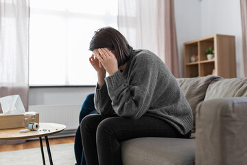 mental health, psychological problem and depression concept - stressed woman with sedative medicine or painkiller on table having headache at home