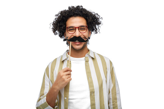 party props, photo booth and people concept - smiling young man with mustache accessory over white background