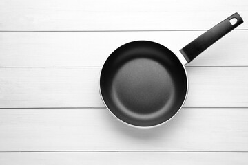 New non-stick frying pan on white wooden table, top view. Space for text