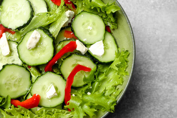 Delicious salad with cucumbers, red bell pepper and feta cheese in bowl on light grey table, closeup