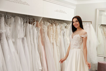 Woman trying on beautiful wedding dress in boutique