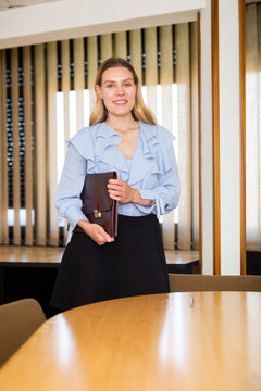 Positive smiling european business woman with briefcase standing in her office