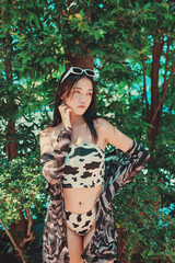 Sexy Asian woman wearing animal cow print bikini with white sunglasses in a fashionable posing in a...