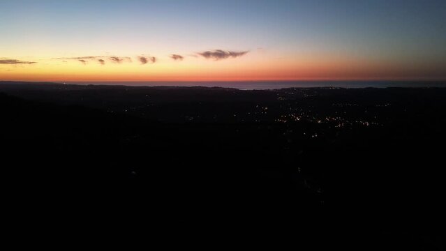 Ascain France coastal town at dusk with lights illuminating the village near the Atlantic Ocean, Aerial flyover shot
