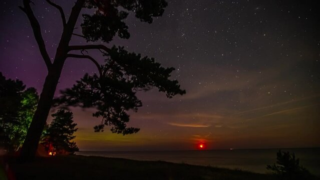 Timelapse shot of milky way galaxy stars along with aurora visible during sunrise over the sea.