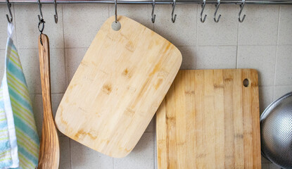 A close-up of cutting wooden boards, a cooking spatula, a kitchen towel hanging on hooks in the...