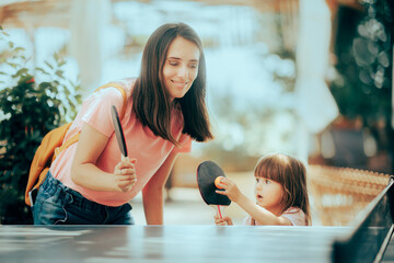 Happy Mother and Daughter Learning to Play Ping Pong Sport. Cheerful family playing leisure sports enjoying table tennis
