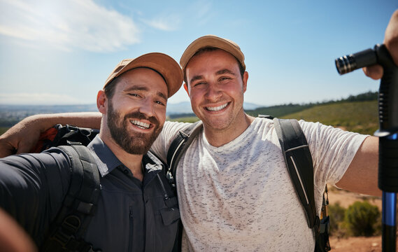 Friends, brothers or hikers taking a selfie while hiking outdoors in nature sharing the experience on social media. Active, fit and athletic men take a picture or a photo while trekking