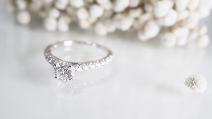 Close up of diamond ring with white flower, sunlight and shadow background. Love, valentine,...