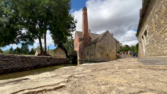 View of the Old Mill museum with undershot waterwheel on the River Eye in Cotswold village Lower Slaughter. Gloucestershire, England