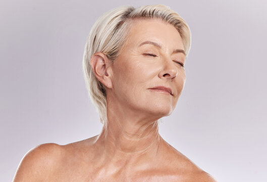 Beauty, skincare and face of a senior woman posing with closed eyes and topless against grey studio background. Happy old, elderly or mature female with glowing skin due to cosmetic self care
