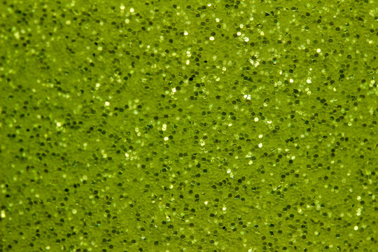 Full frame abstract background of shimmering green glitter texture with selective focus

