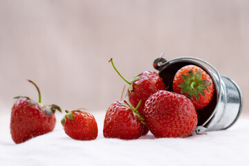 Ripe juicy strawberries in a bucket on a light background.Summer composition with strawberries.