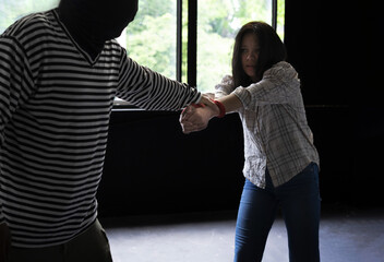 woman victim being tied in the dark room and pulling against with a robber, concept for women,...