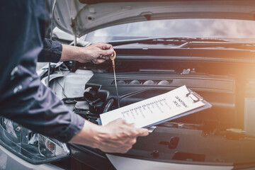 Car mechanical engineering checking oil level at workshop garage.