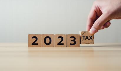 Holding a wooden block with tax 2023. Concept of planning to pay taxes in 2023. paying the tax...