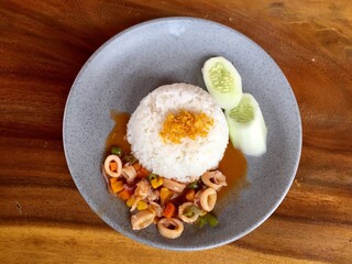 a serving of sweet and sour squid complete with rice and cucumber. Asian food.