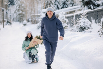 Smiling man giving sledding ride to woman. Love and leisure concept. High quality photo