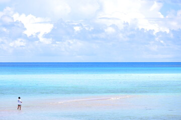  遠浅の海に立つ男の人