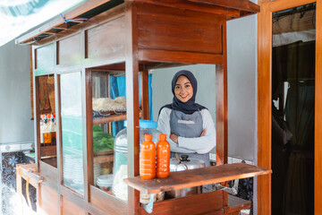 Muslim woman seller wearing apron smiling while standing with crossed hands behind cart