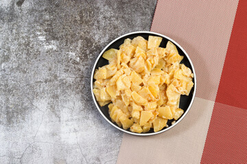 Sour Cream and Onion Stewed Potatoes on a round plate on a dark background. Top view, flat lay