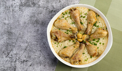 One-Pan Chicken Drumsticks with Rice in a white baking dish on a dark grey background. Top view, flat lay