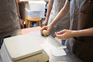 The process of learning the craft of baking in a small bakery, molding rolls. Front view.