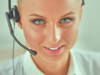 Portrait of pretty young female operator sitting at office desk with headset