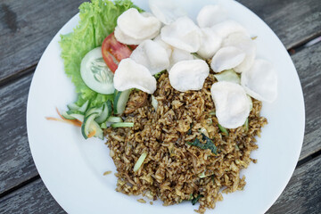 Nasi goreng jawa or javanese fried rice chicken with vegetable and crackers on white plate. Indonesian food Asian cuisine