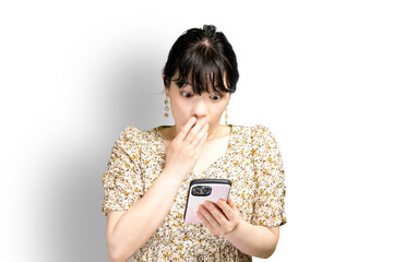 スマホ画面を見て驚く女性