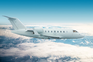 White modern executive jetliner flies over snow-covered mountains