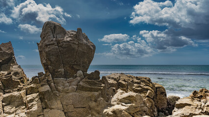 Fototapeta premium Picturesque granite boulders against a background of blue sky, clouds, turquoise ocean. Seychelles. Mahe