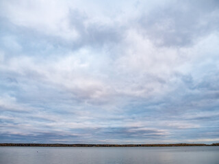 Lake with pine and birch forest on the shores at summer or early autumn sunset.